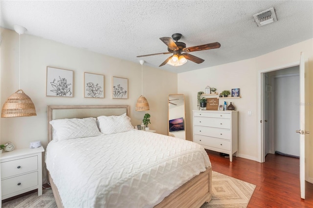 bedroom with dark wood-type flooring, a textured ceiling, and ceiling fan