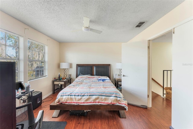 bedroom with ceiling fan, wood-type flooring, and a textured ceiling