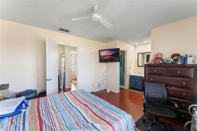 bedroom featuring a textured ceiling, dark hardwood / wood-style floors, ceiling fan, and ensuite bathroom