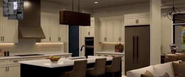 kitchen featuring sink, black appliances, hanging light fixtures, a center island with sink, and white cabinets