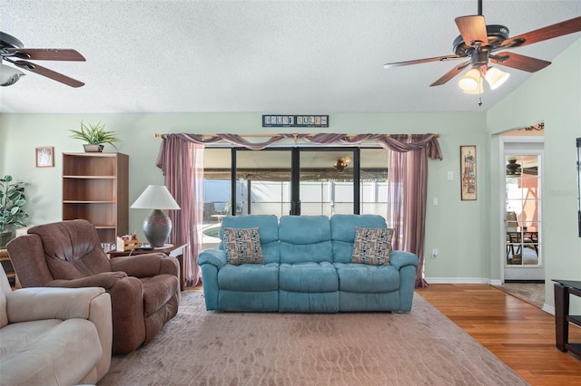 living room featuring hardwood / wood-style flooring, ceiling fan, and a textured ceiling