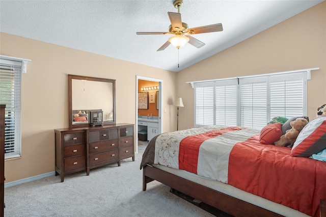 bedroom with ceiling fan, ensuite bathroom, vaulted ceiling, and light carpet