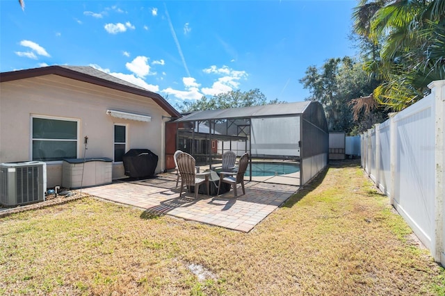 rear view of property featuring a fenced in pool, a lanai, a yard, a patio, and central air condition unit