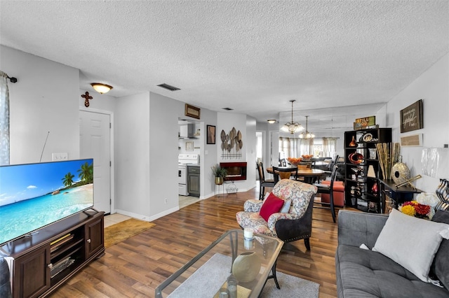 living room with hardwood / wood-style flooring, a chandelier, and a textured ceiling