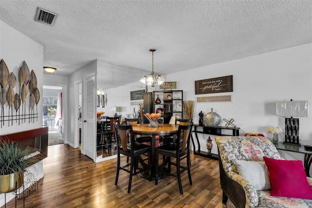 dining space featuring a chandelier, dark hardwood / wood-style floors, and a textured ceiling