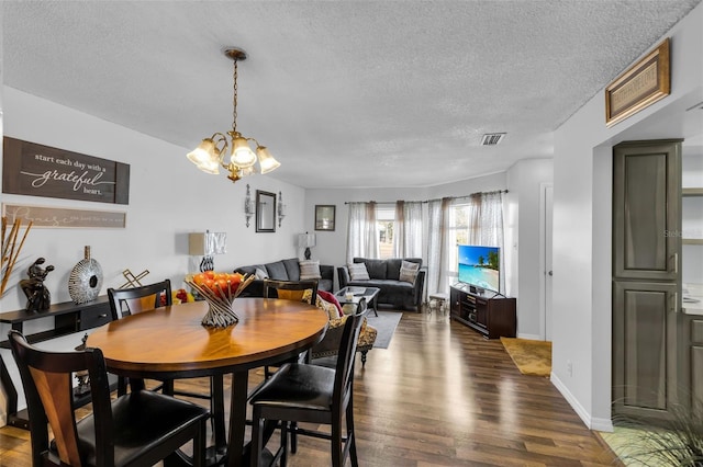 dining area featuring an inviting chandelier, dark hardwood / wood-style floors, and a textured ceiling