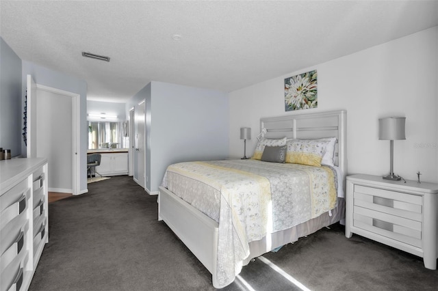 carpeted bedroom featuring ensuite bathroom and a textured ceiling