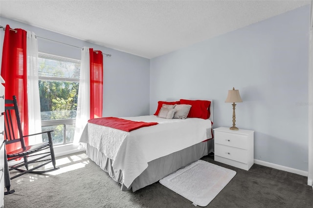 bedroom featuring a textured ceiling, multiple windows, and dark colored carpet