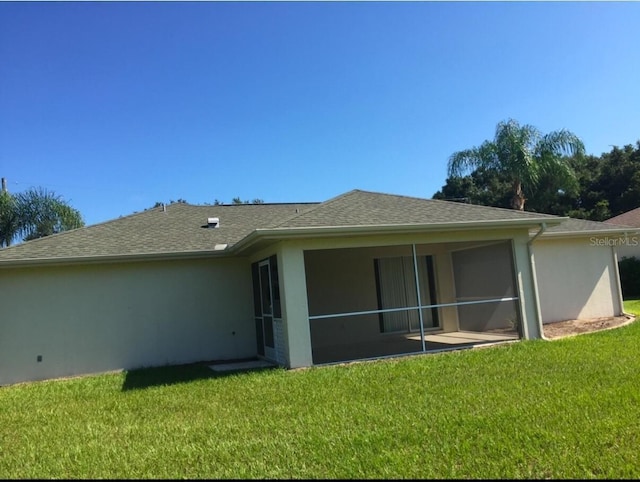 rear view of property featuring a lawn and a sunroom