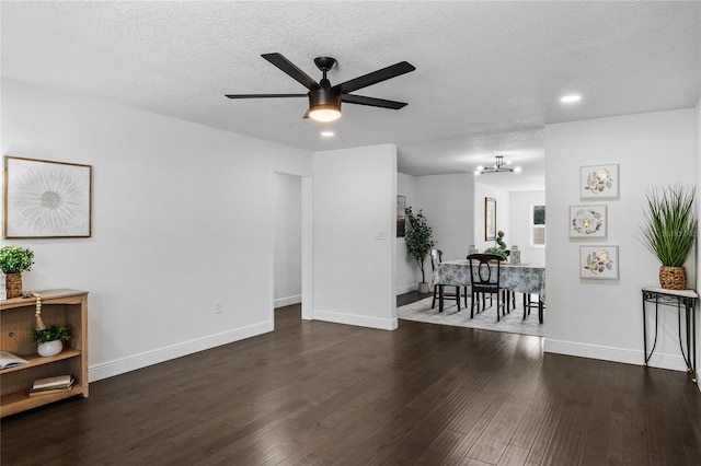 living room featuring ceiling fan, dark hardwood / wood-style floors, and a textured ceiling