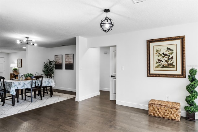 dining area with wood-type flooring and a textured ceiling