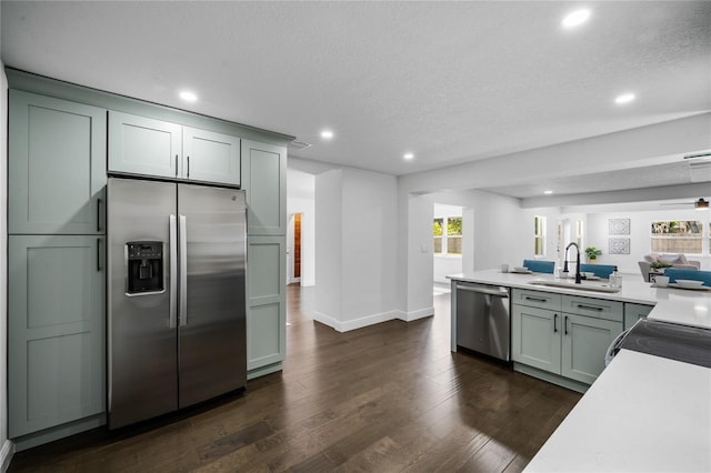 kitchen with sink, stainless steel appliances, dark hardwood / wood-style floors, and a textured ceiling