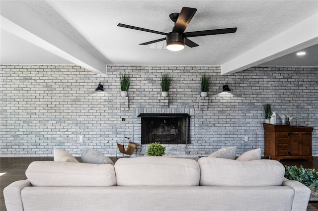 living room featuring beamed ceiling, ceiling fan, brick wall, and a textured ceiling