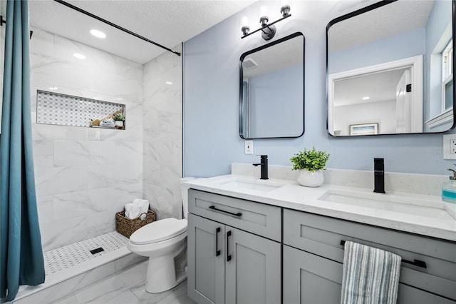 bathroom with vanity, toilet, a textured ceiling, and a tile shower