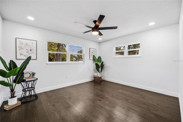 unfurnished room featuring ceiling fan, plenty of natural light, dark hardwood / wood-style floors, and a textured ceiling