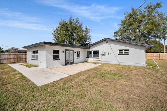 back of property with a yard and a patio area