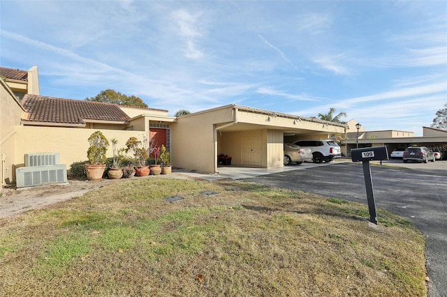 view of front of property with central AC unit, a front yard, and a carport