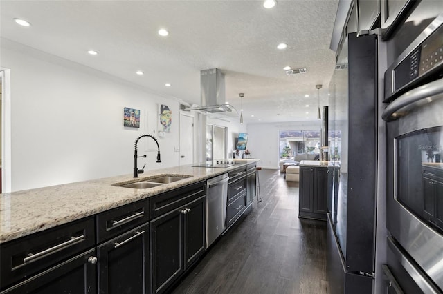 kitchen with sink, hanging light fixtures, appliances with stainless steel finishes, island exhaust hood, and light stone countertops