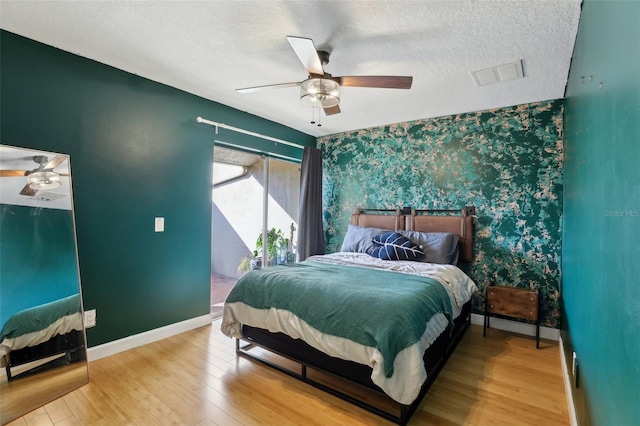 bedroom featuring ceiling fan, wood-type flooring, and a textured ceiling