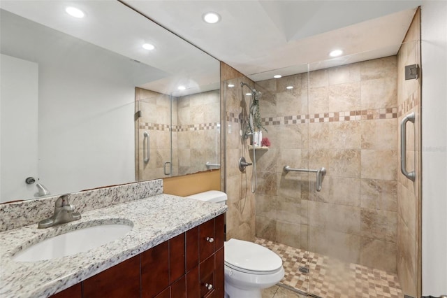 bathroom with vanity, a shower with door, and toilet