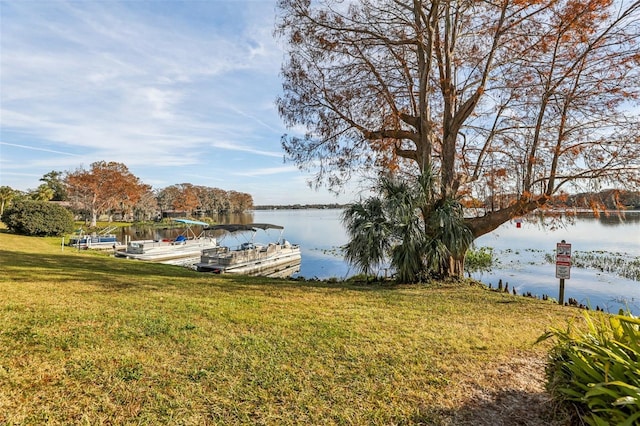 view of dock with a water view and a yard