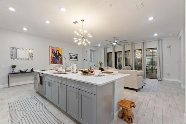 kitchen featuring sink, decorative light fixtures, stainless steel dishwasher, and a center island with sink