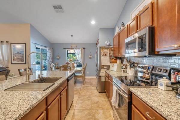 kitchen featuring hanging light fixtures, light stone countertops, sink, and appliances with stainless steel finishes