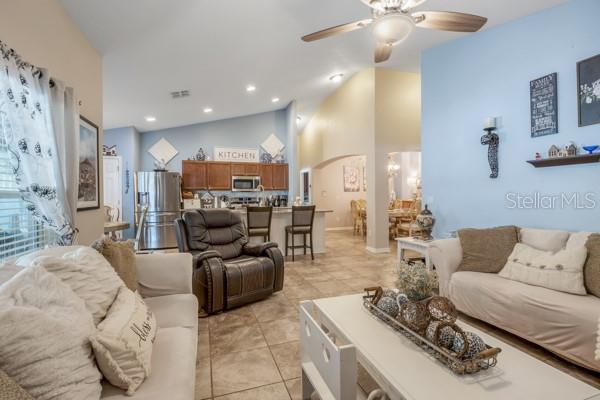 tiled living room featuring ceiling fan and lofted ceiling