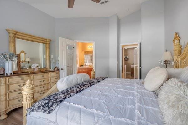 bedroom with hardwood / wood-style floors, vaulted ceiling, ceiling fan, and ensuite bathroom