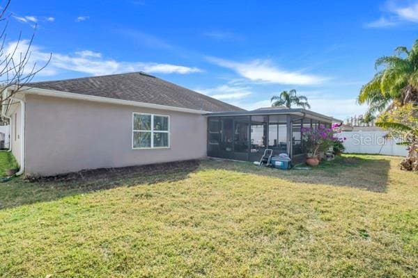 rear view of house featuring a lawn and a sunroom