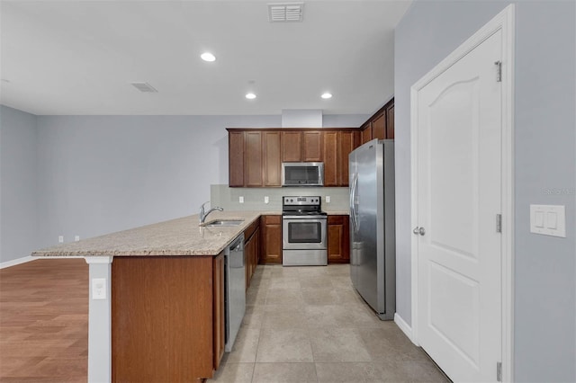 kitchen with appliances with stainless steel finishes, sink, a breakfast bar area, backsplash, and kitchen peninsula