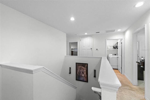 hallway with light colored carpet and washer / dryer