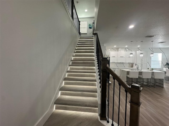 stairway featuring sink, hardwood / wood-style floors, and a textured ceiling