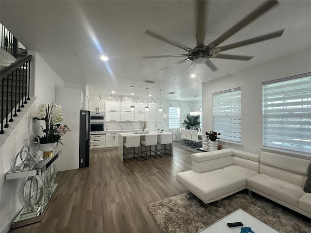 living room with ceiling fan, dark hardwood / wood-style floors, sink, and a textured ceiling