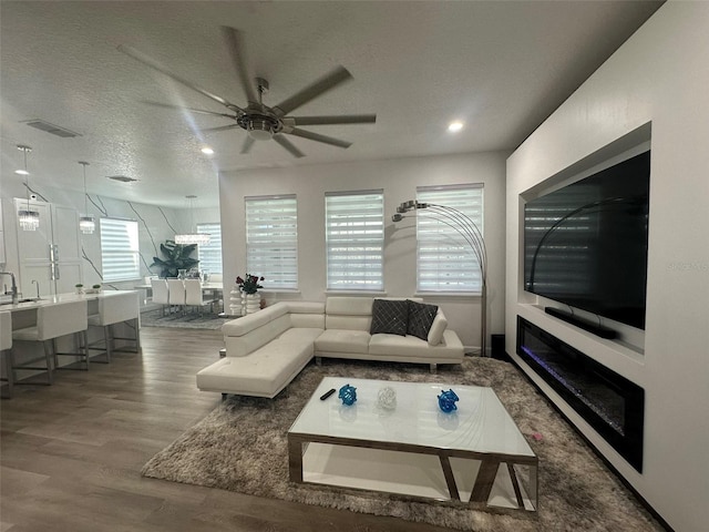 living room with ceiling fan, hardwood / wood-style flooring, and a textured ceiling