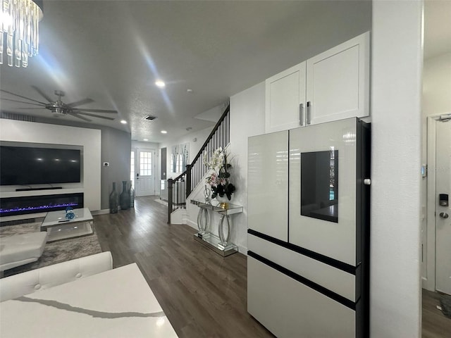 interior space with ceiling fan, dark hardwood / wood-style flooring, a textured ceiling, and white cabinets