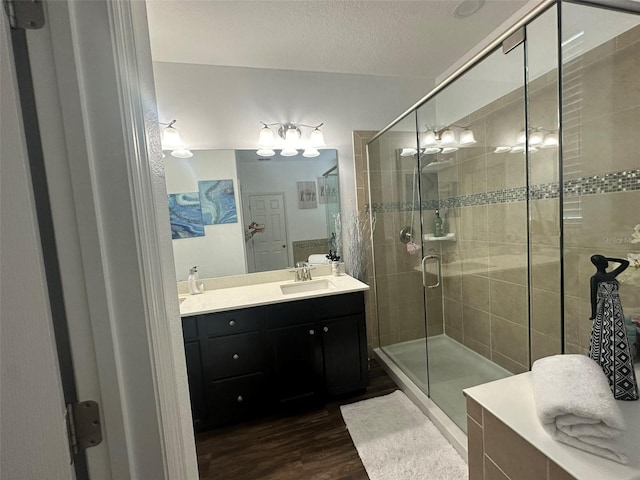 bathroom featuring wood-type flooring, vanity, a textured ceiling, and a shower with shower door