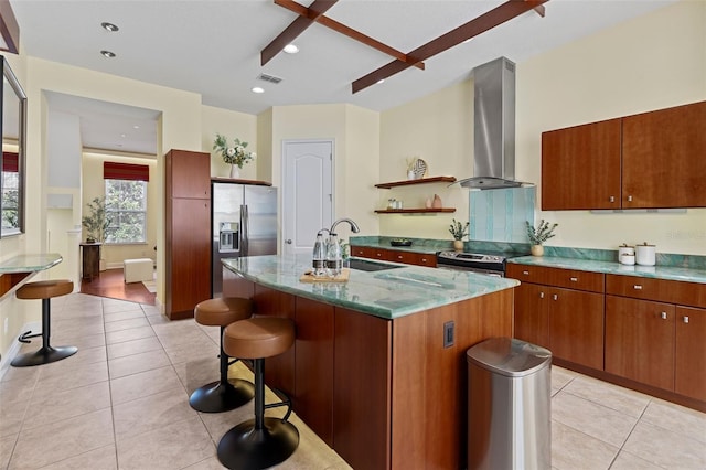 kitchen featuring sink, a breakfast bar area, a kitchen island with sink, stainless steel appliances, and wall chimney range hood