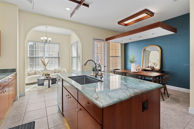 kitchen featuring sink, decorative light fixtures, stainless steel dishwasher, an island with sink, and a notable chandelier