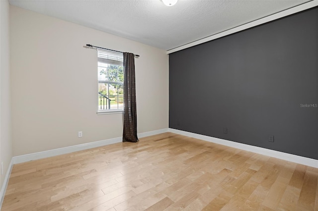 unfurnished room with a textured ceiling and light hardwood / wood-style floors