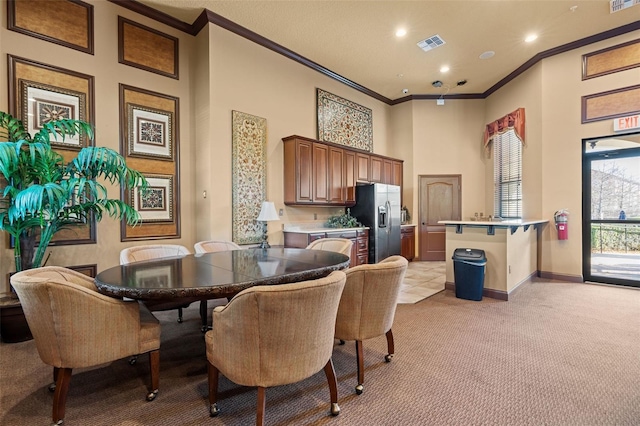 carpeted dining room with a towering ceiling and ornamental molding