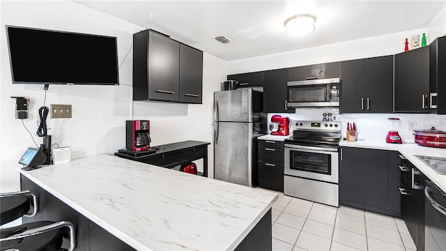 kitchen with light tile patterned floors, backsplash, and appliances with stainless steel finishes