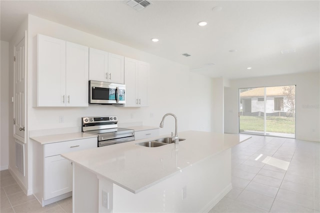 kitchen featuring sink, stainless steel appliances, white cabinets, and a center island with sink