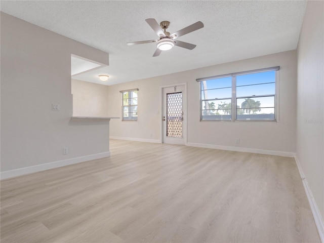 empty room featuring ceiling fan, light hardwood / wood-style flooring, and a textured ceiling