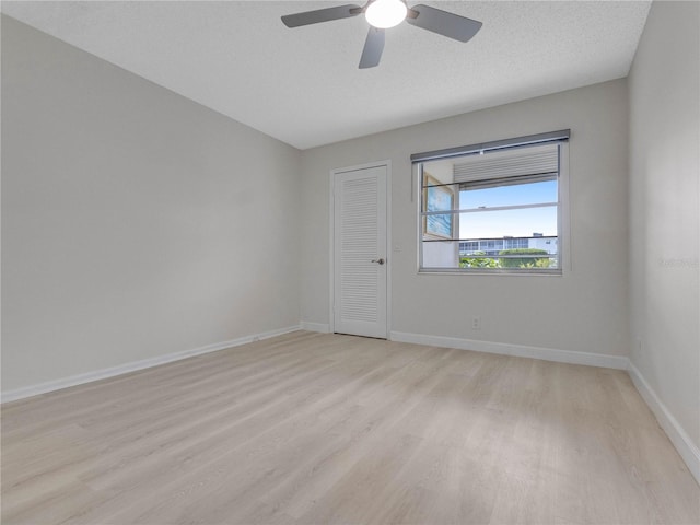 empty room with ceiling fan, a textured ceiling, and light wood-type flooring