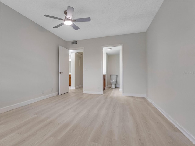 unfurnished bedroom featuring ceiling fan, ensuite bathroom, a textured ceiling, and light wood-type flooring