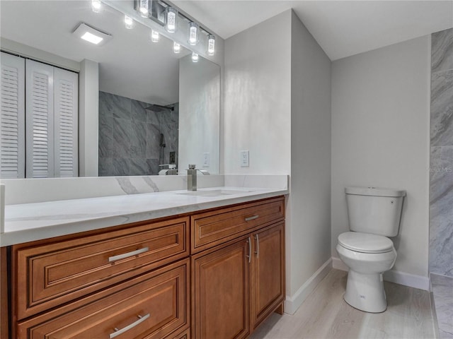 bathroom with vanity, wood-type flooring, tiled shower, and toilet