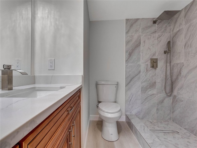 bathroom with tiled shower, vanity, and toilet