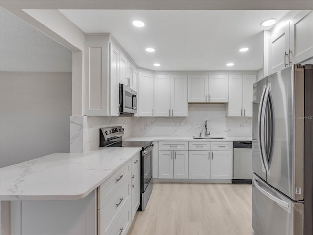 kitchen featuring sink, white cabinets, light stone counters, kitchen peninsula, and stainless steel appliances