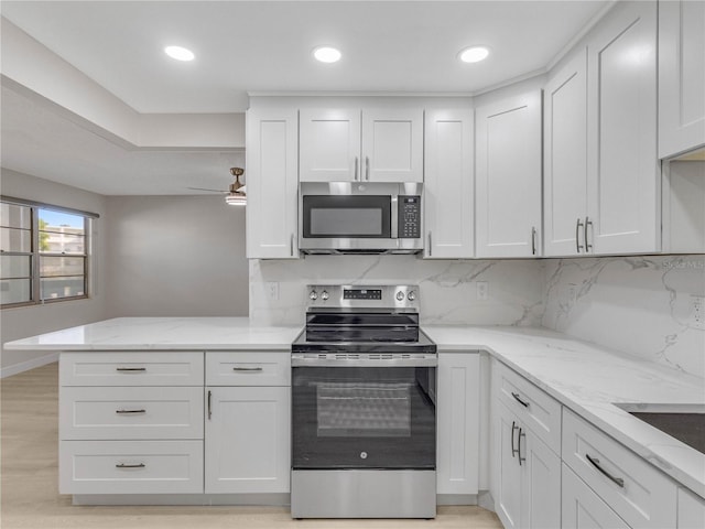 kitchen featuring ceiling fan, appliances with stainless steel finishes, tasteful backsplash, white cabinets, and kitchen peninsula